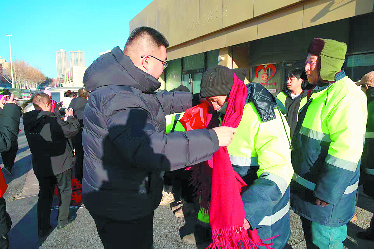 環(huán)衛(wèi)工人領(lǐng)到愛心圍巾。 (圖片由李建學(xué)提供)